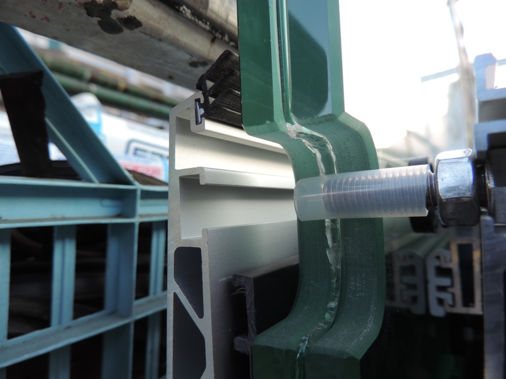 particolare dell'asola nel vetro della pensilina per alloggiare il perno di sicurezza