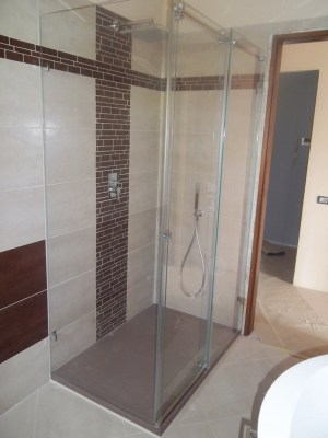 box doccia in cristallo con porta scorrevole e gli altri vetri senza fissaggi con telai perimetralil ma vetro fissato direttamente su piastrelle