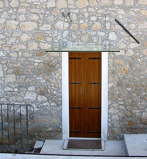 pensilina in vetro a protezione della porta in legno