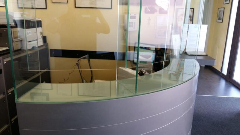 pannello in vetro anticontagio da covid posata su banco curvo di reception
