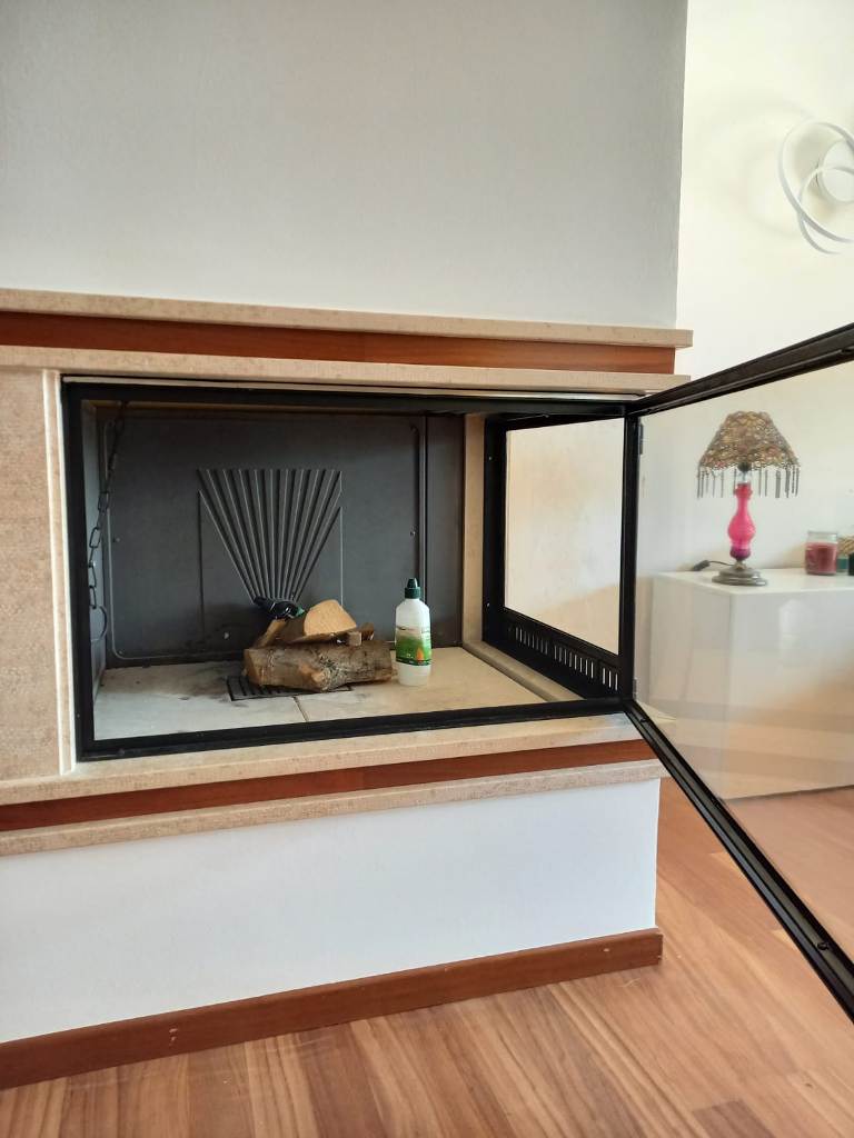 particolare dello sportello aperto di un telaio in ferrro con vetro ceramico per chiudere un camino